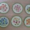 Vintage metalen onderzetters met geborduurd bloemmotief
